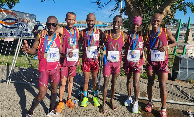Distance squad in maroon and gold vests with medals after a road race