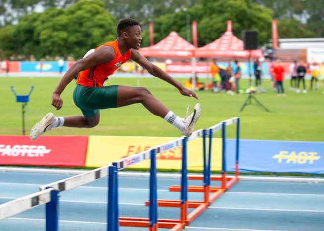 Hurdler in mid-flight over a hurdle at a track meet